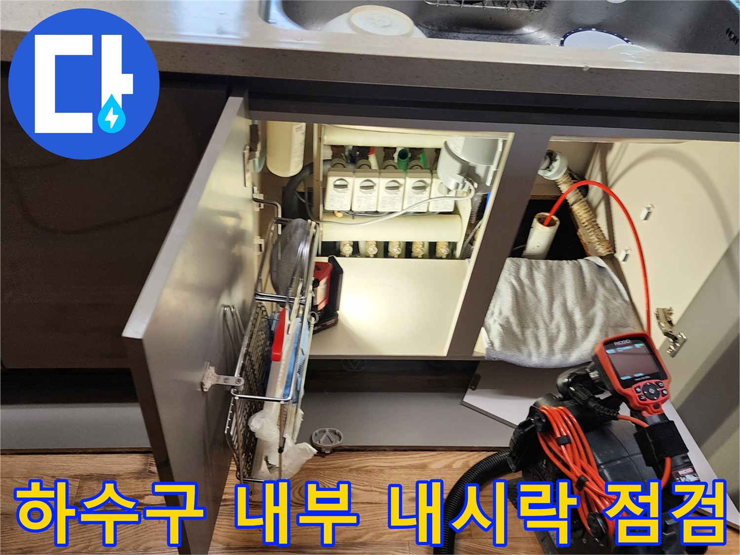 싱크대 밑 하부장 내부의 복잡한 배관과 진단용 전문 장비 세팅
