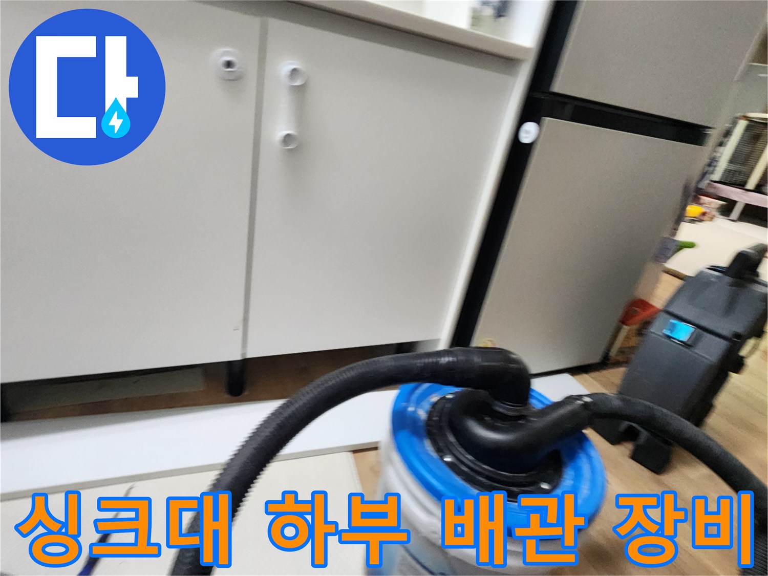 주방 싱크대 아래쪽 배관 상태를 확인하기 위해 설치된 흡입 호스와 수거통