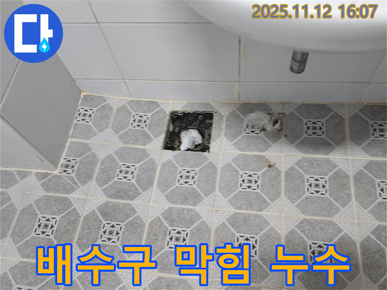 세면대 배수구 주변에 물이 고여있고, 배수구 안이 막혀있는 모습 - 복합적인 문제임을 보여줍니다.