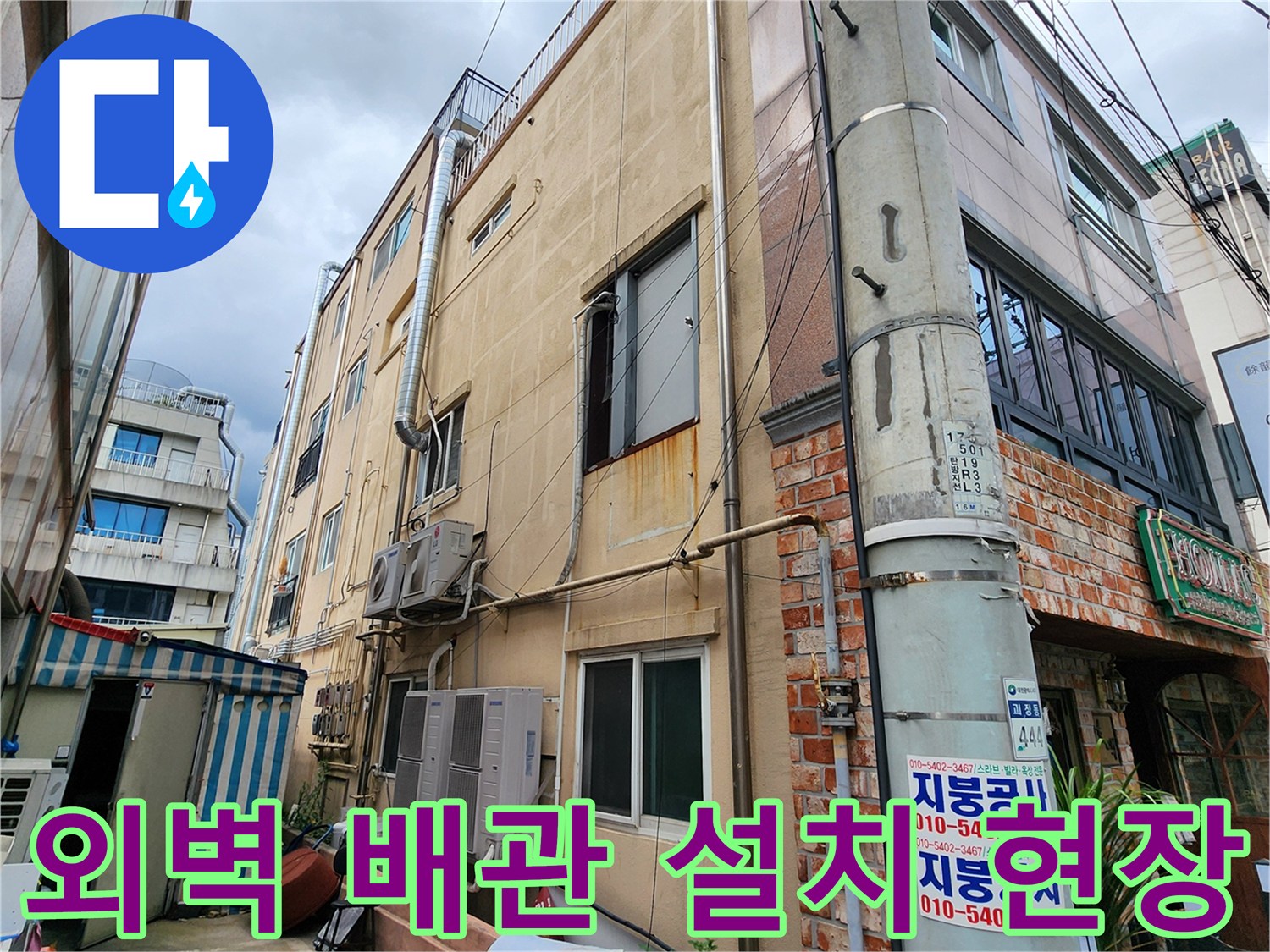건물 외측 벽면에 돌출된 에어컨 배관과 금속 관로의 배치 상태