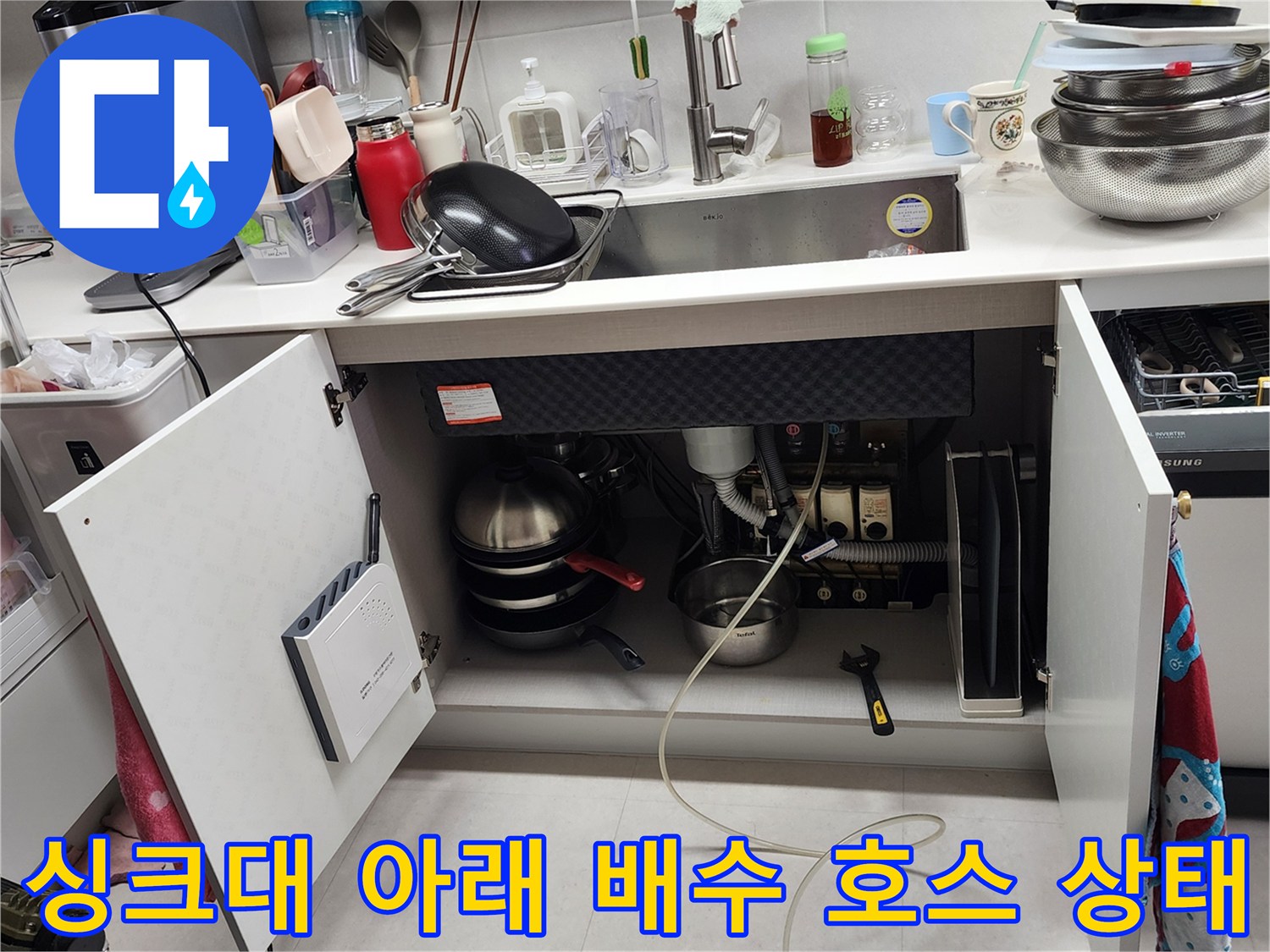하부장 내부에 설치된 싱크대 배수 호스와 연결 부위의 모습입니다.