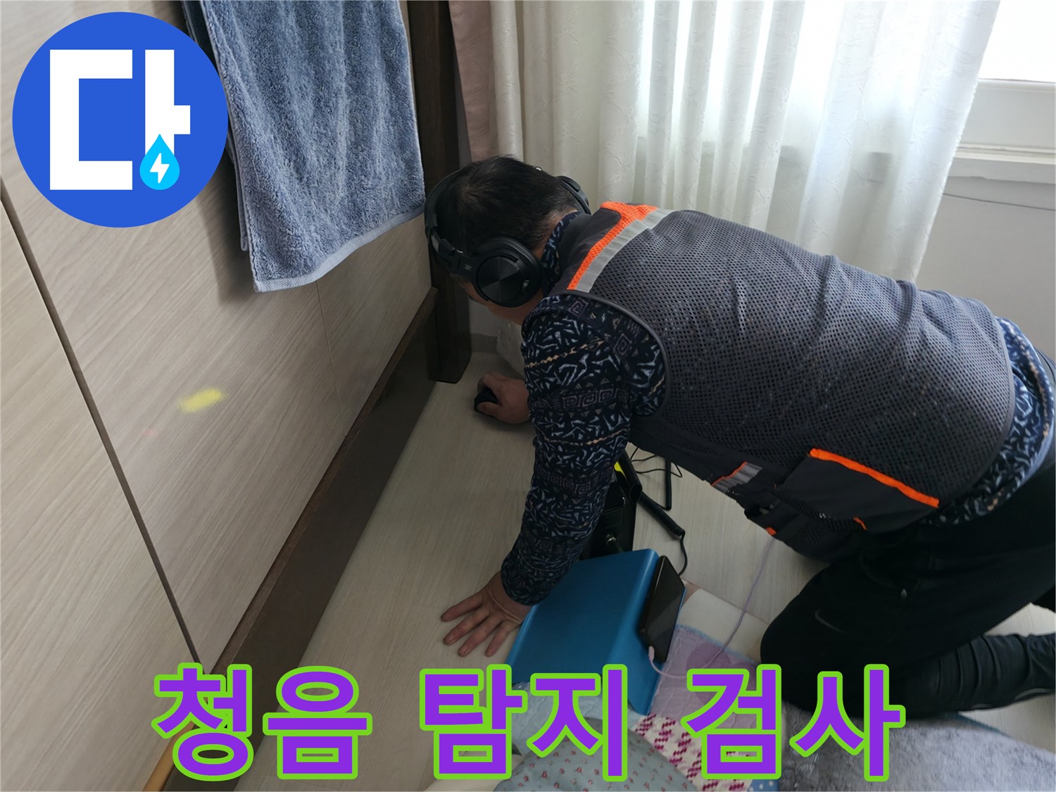 누수 전문가가 - 헤드폰을 착용하고 - 청음 탐지기로 누수음을 듣고 있는 모습
