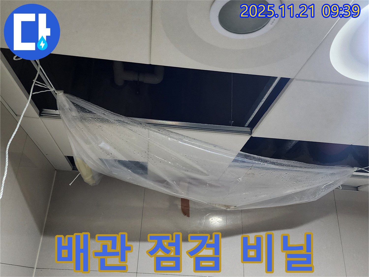 천장 배관 연결 부위 누수 가능성을 점검하기 위해 - 비닐 덮개를 설치하고 연결 부위를 집중적으로 살펴보고 있습니다.
