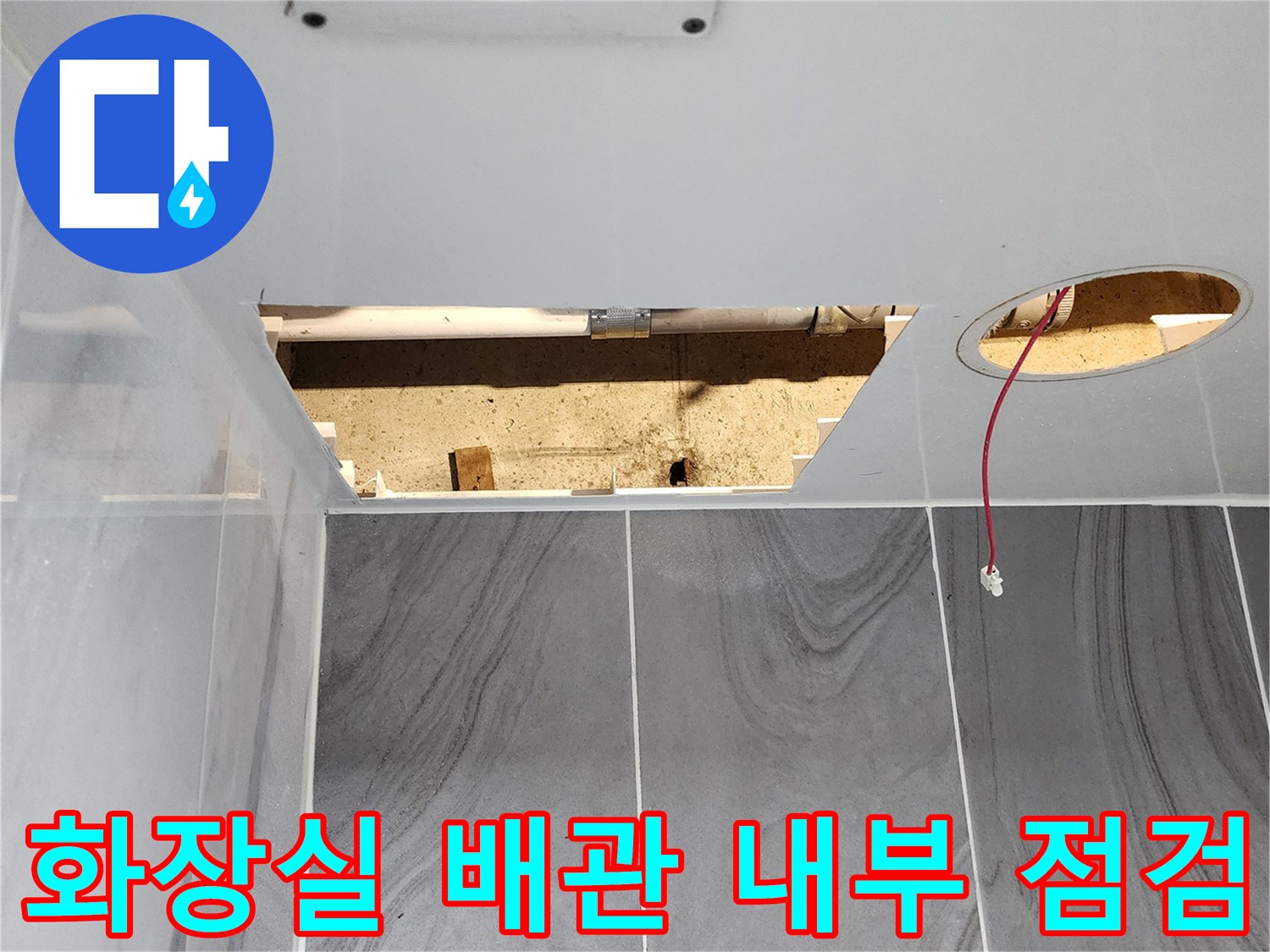 타일 아래 노출된 배수 배관과 전기선
