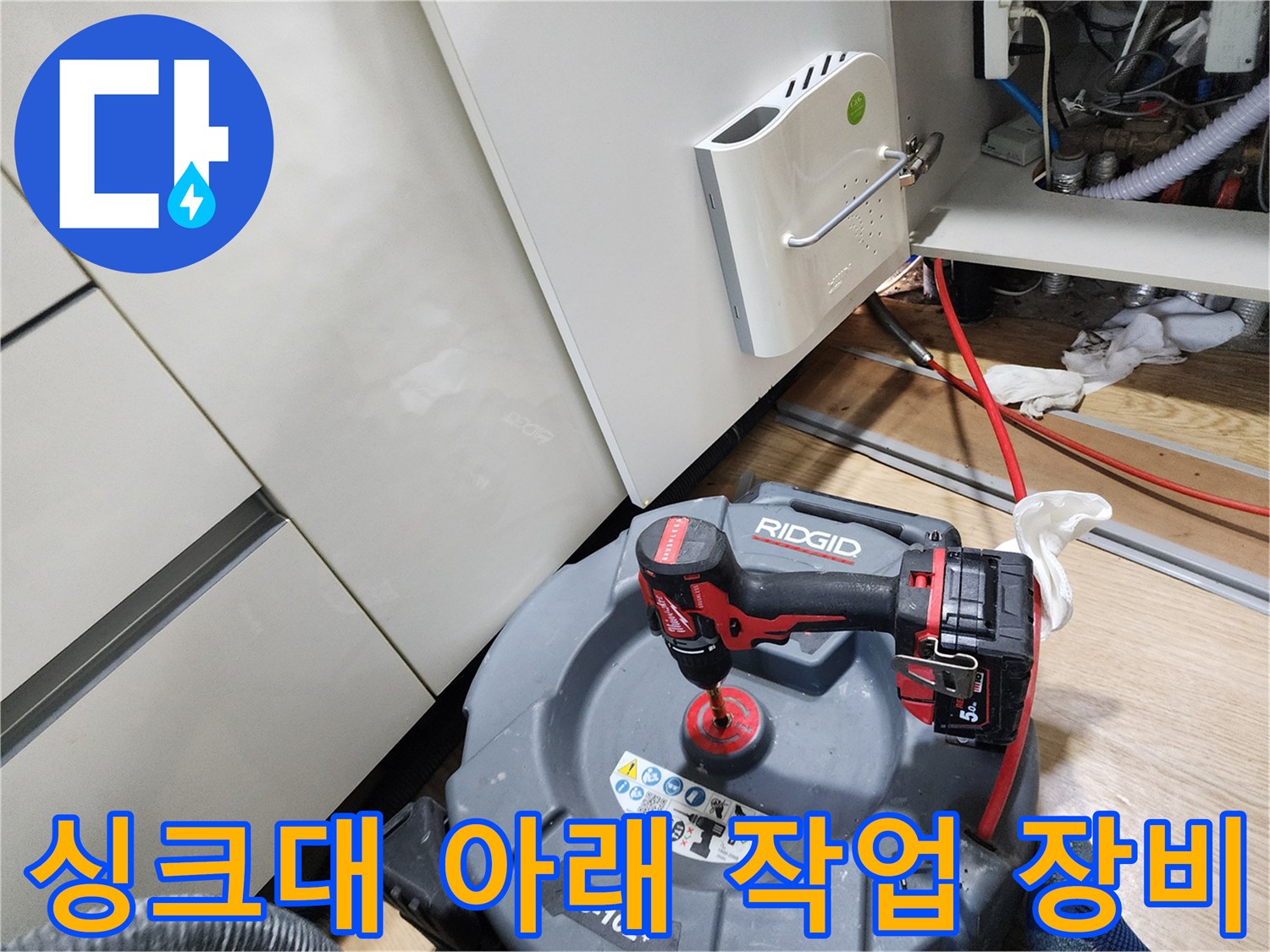 배수관 점검을 위해 싱크대 하단에 배치된 전동 드릴과 도구들