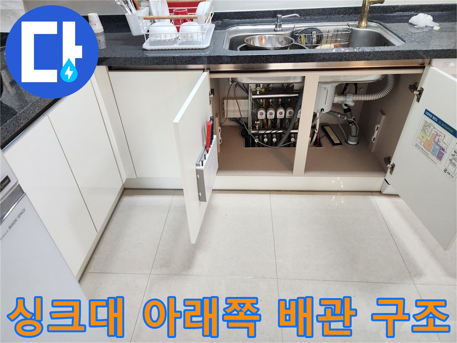 싱크대 밑 하부장 내부의 복잡하게 얽힌 배수 호스들