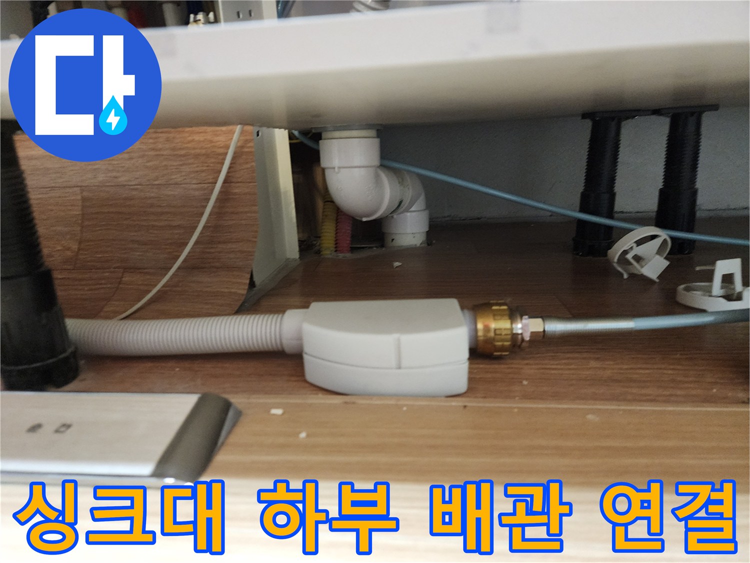 싱크대 아래쪽의 흰색 플라스틱 관과 주름진 호스의 모습