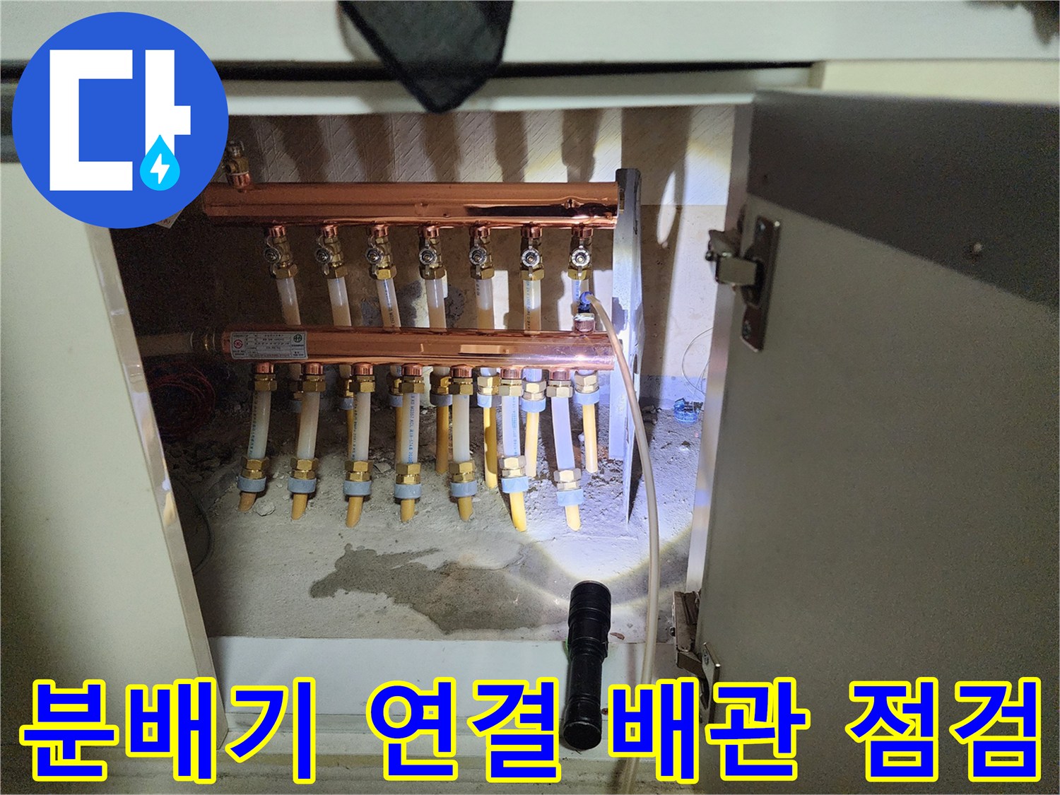 싱크대 하부장 내부의 금속제 분배기와 노란색 밸브 부속품들