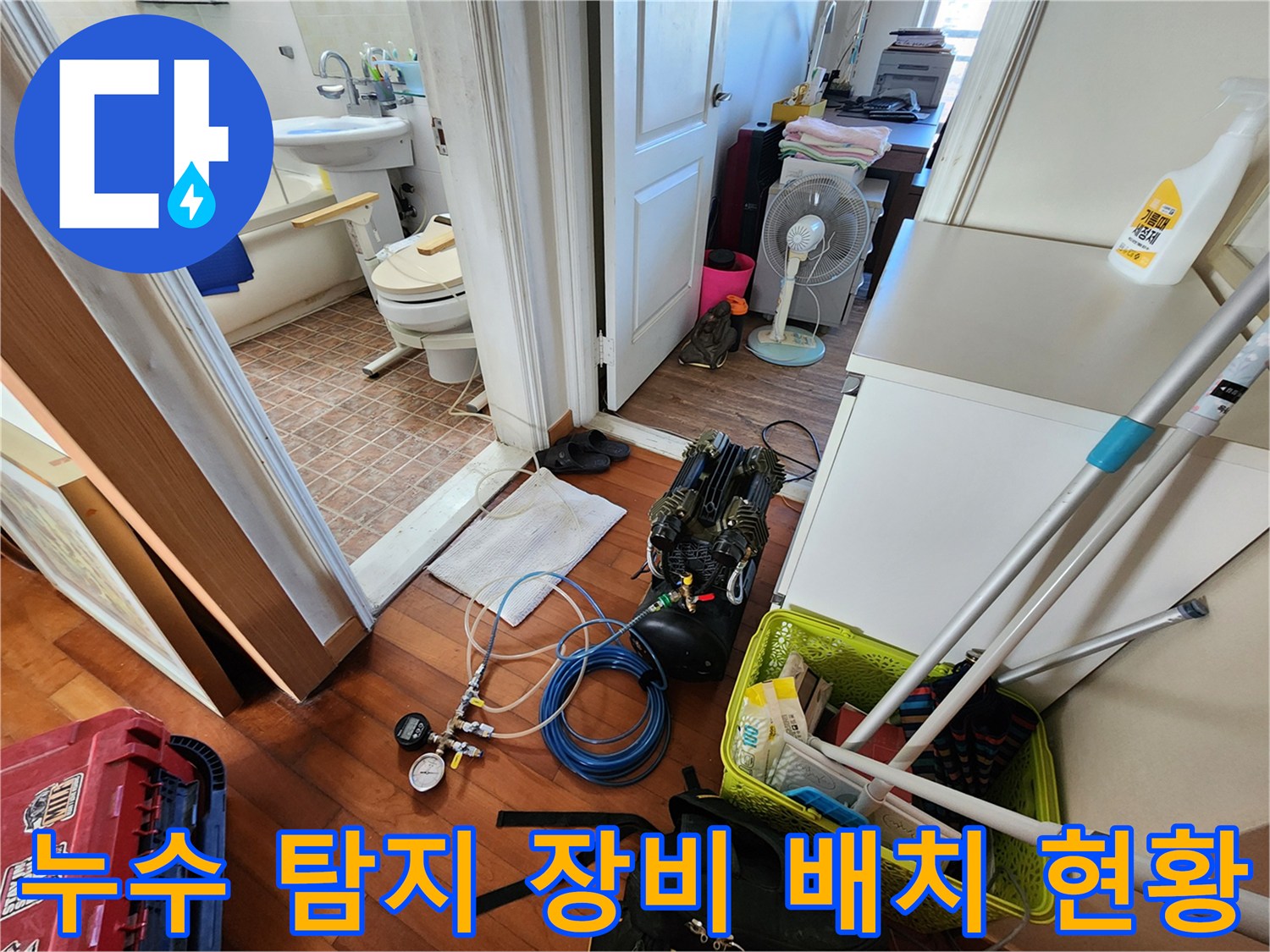 욕실 입구 바닥에 놓인 배관 검사용 공압 게이지와 파란색 호스
