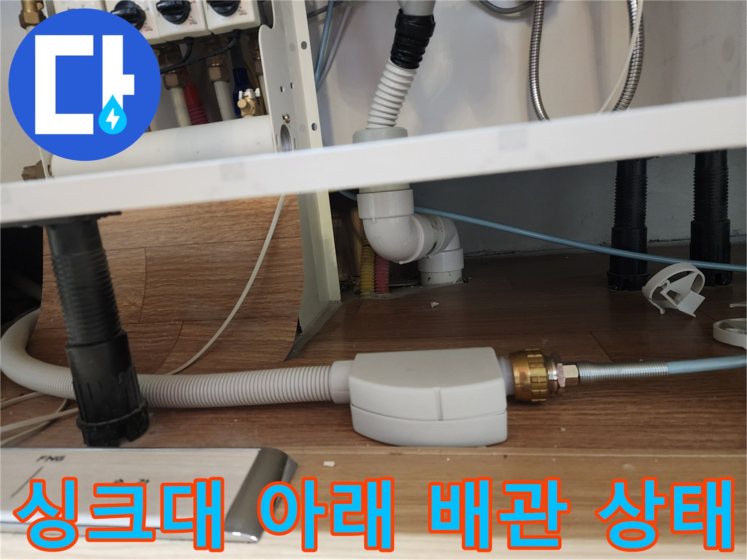 주방 싱크대 하단의 배수 호스와 급수 부속 상세 촬영