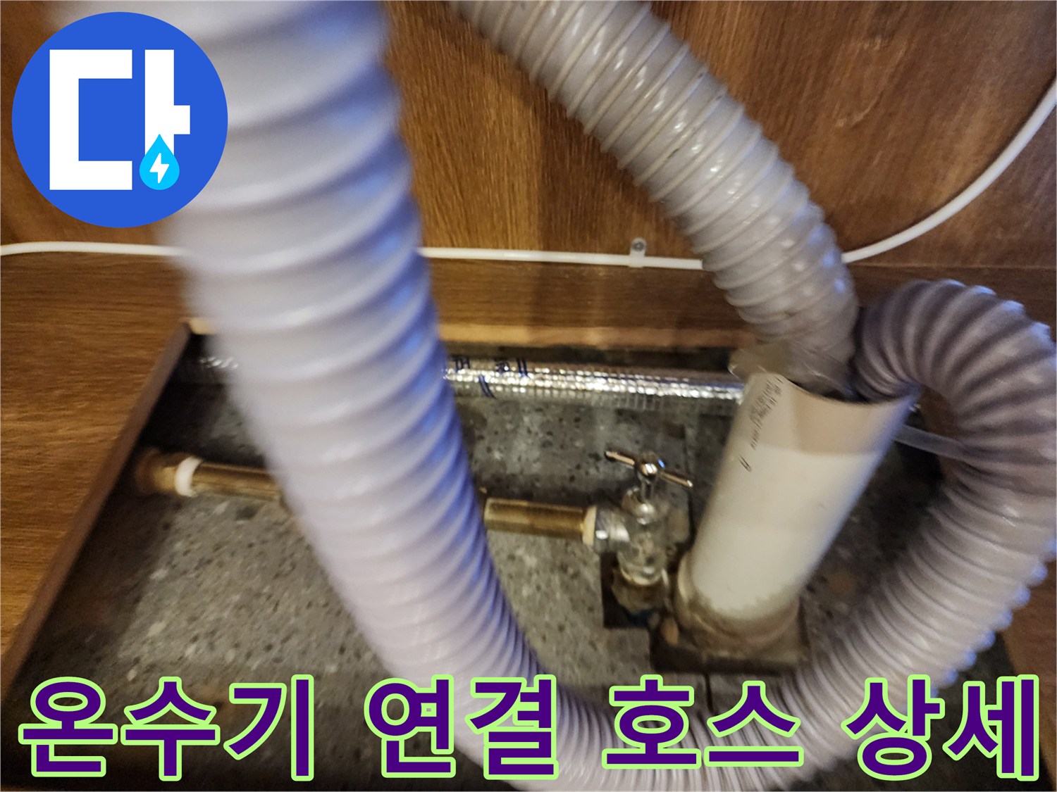 싱크대 하부장 내부-회색 주름관과 금속 배관 접합부