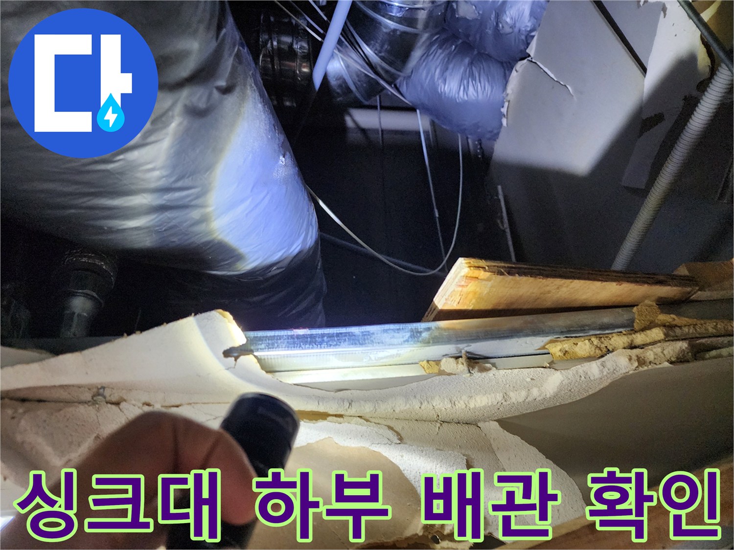 손전등으로 비춘 싱크대 아래쪽 배관 주변의 습한 상태와 마감재 모습