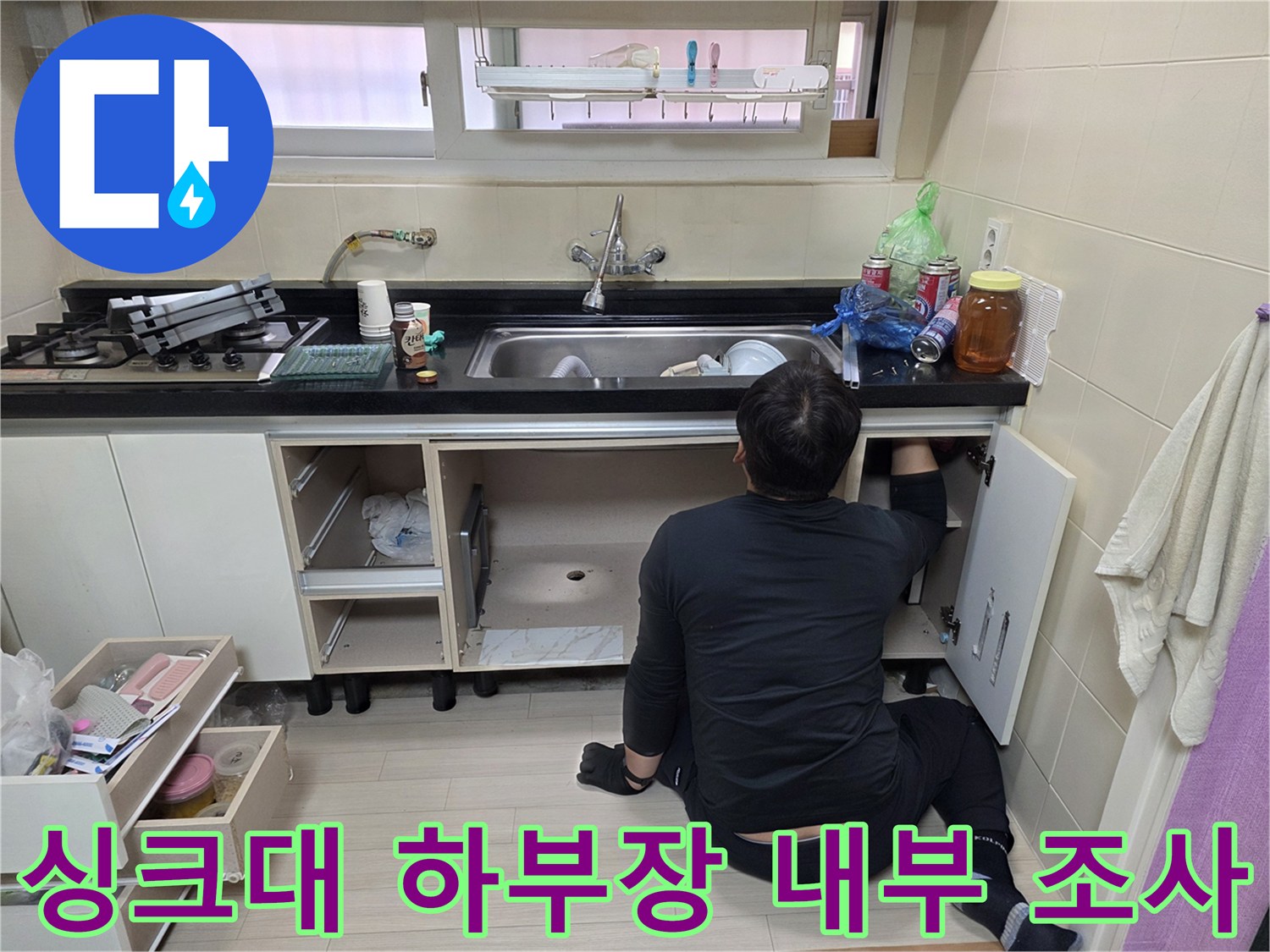 싱크대 아래쪽 배관 부위를 확인하기 위해 작업 중인 현장 모습