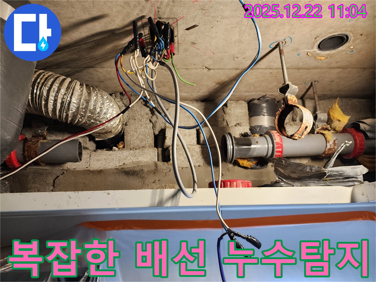 복잡하게 얽힌 천장 배선 속에서 누수 지점을 찾아내는 - 누수탐지 전문가의 숙련된 기술을 보여주는 이미지입니다.