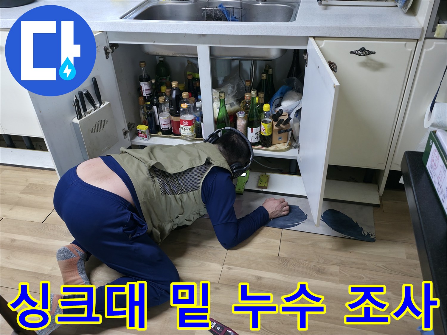 싱크대 하단 배관의 누수 지점을 찾기 위해 낮은 자세로 작업하는 엔지니어