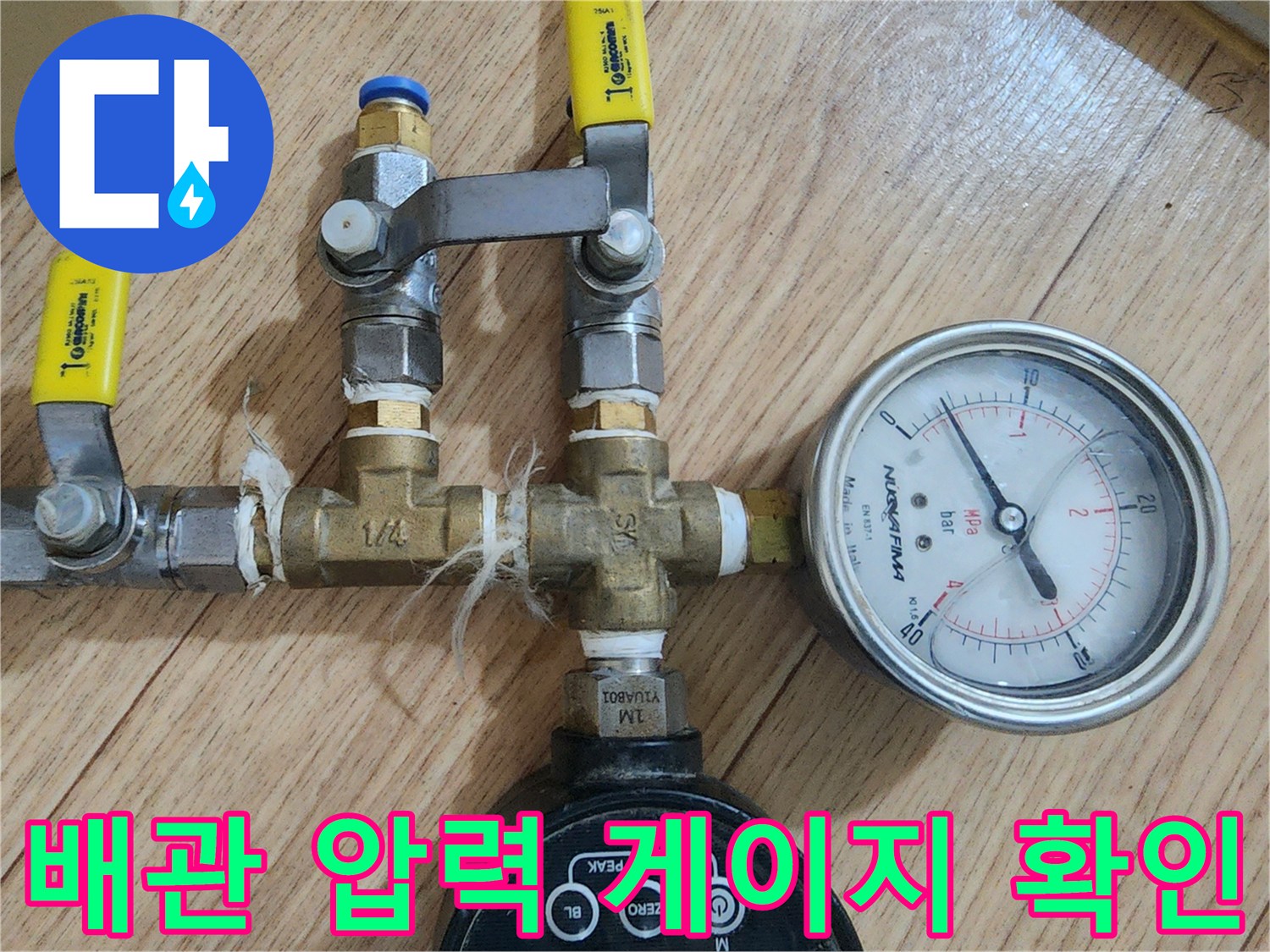 노란색 밸브 핸들과 아날로그 압력계가 설치된 배관 부위