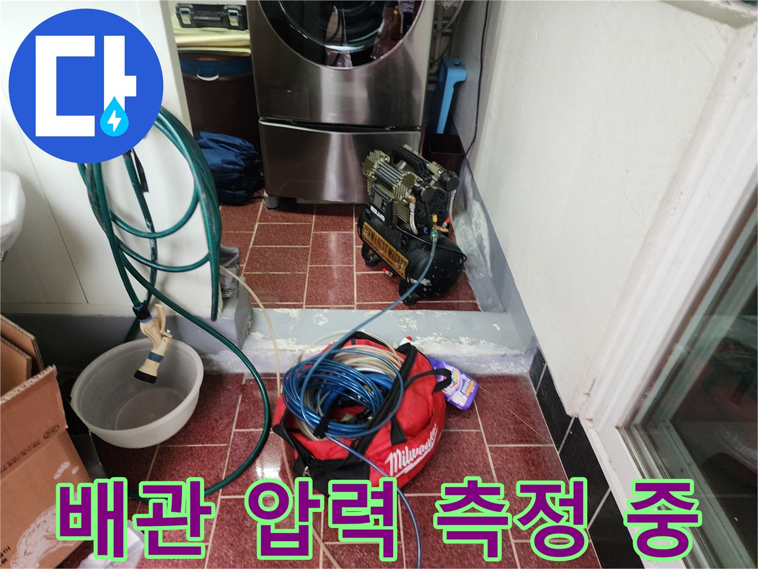 세탁실 바닥 타일 위로 연결된 누수 탐지용 호스와 게이지