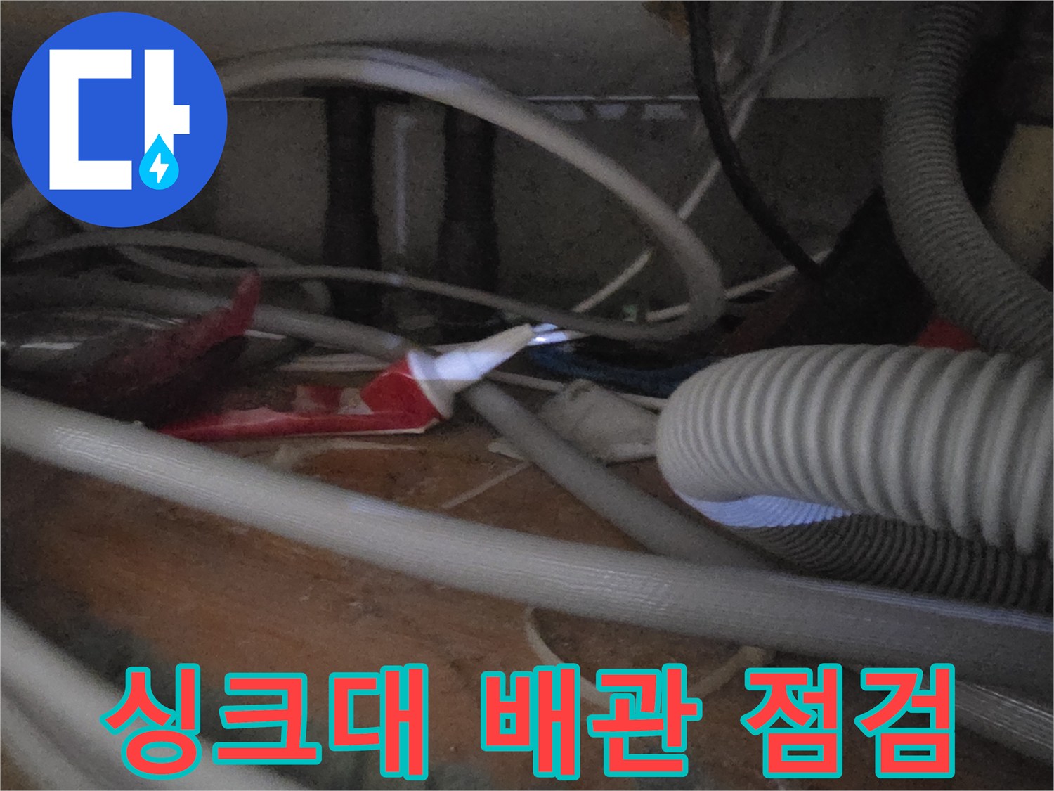 싱크대 하부장 내부의 복잡한 배관과 호스 상태 확인