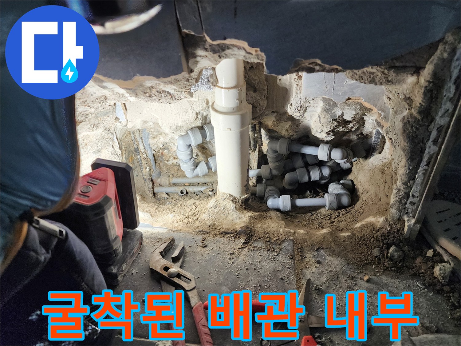 바닥을 파내어 드러난 변기 연결 배관과 작업 도구