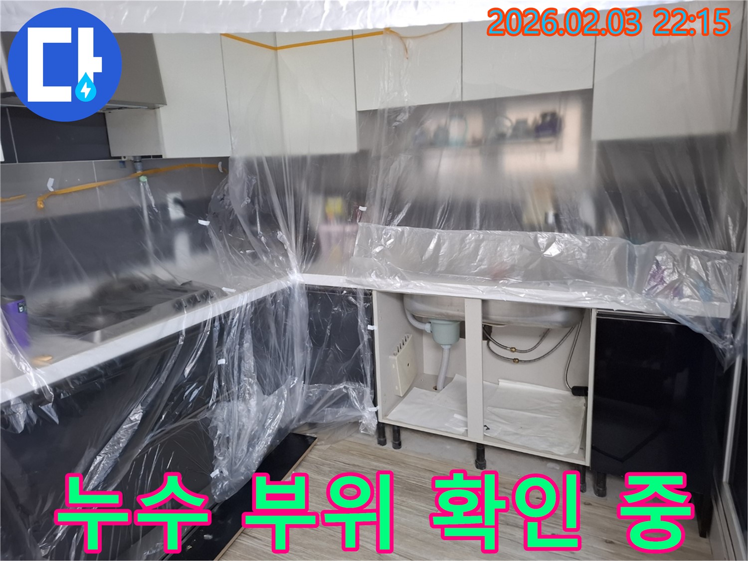 누수 부위 확인 중 - 씽크대 하부에서 누수 부위를 찾기 위해 꼼꼼하게 살펴보고 있습니다 - 숙련된 기술로 문제 해결!