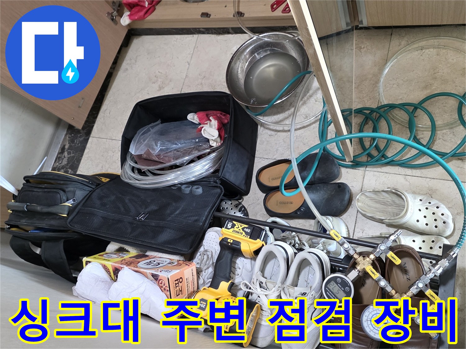 싱크대 하부장 내부의 배관 점검용 공구와 측정 장비 세트