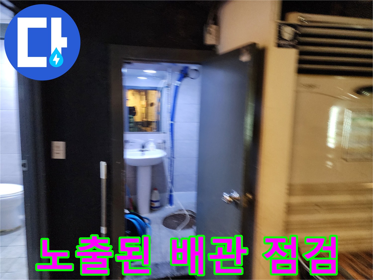 세면대 아래쪽 파란색 호스와 바닥 배수구 주변의 노출된 배관 시설물
