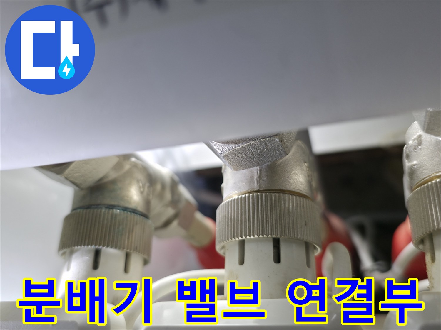 난방 분배기의 금속 밸브와 하얀색 배관 부근 상세 사진