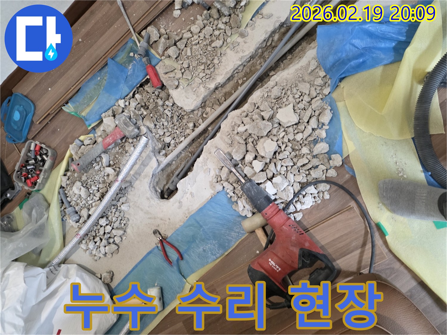 누수-공사-현장에서-바닥이-파쇄되고-배관이-노출된-모습-드릴과-망치-등-공구들이-놓여있습니다.