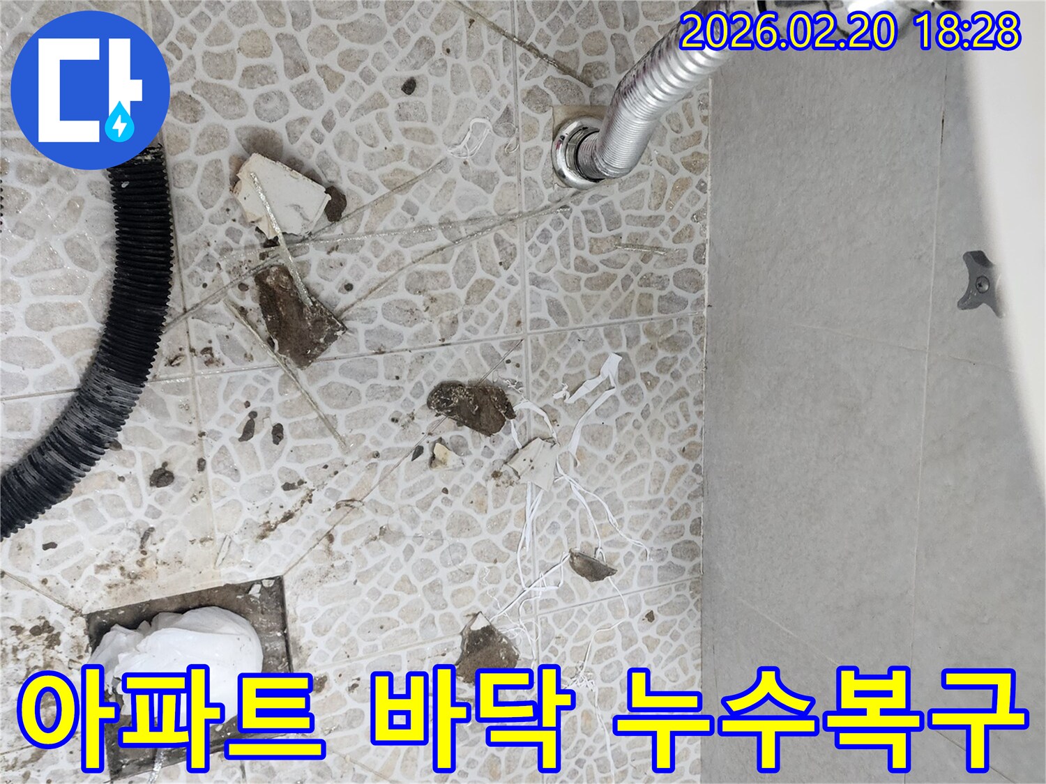 이 이미지는 장한동 아파트에서 발생한 배관 파열로 인한 바닥 누수 현장을 보여주며-손상된 부분을 복구하기 위해-전문가가 바닥재를 제거한 모습입니다.