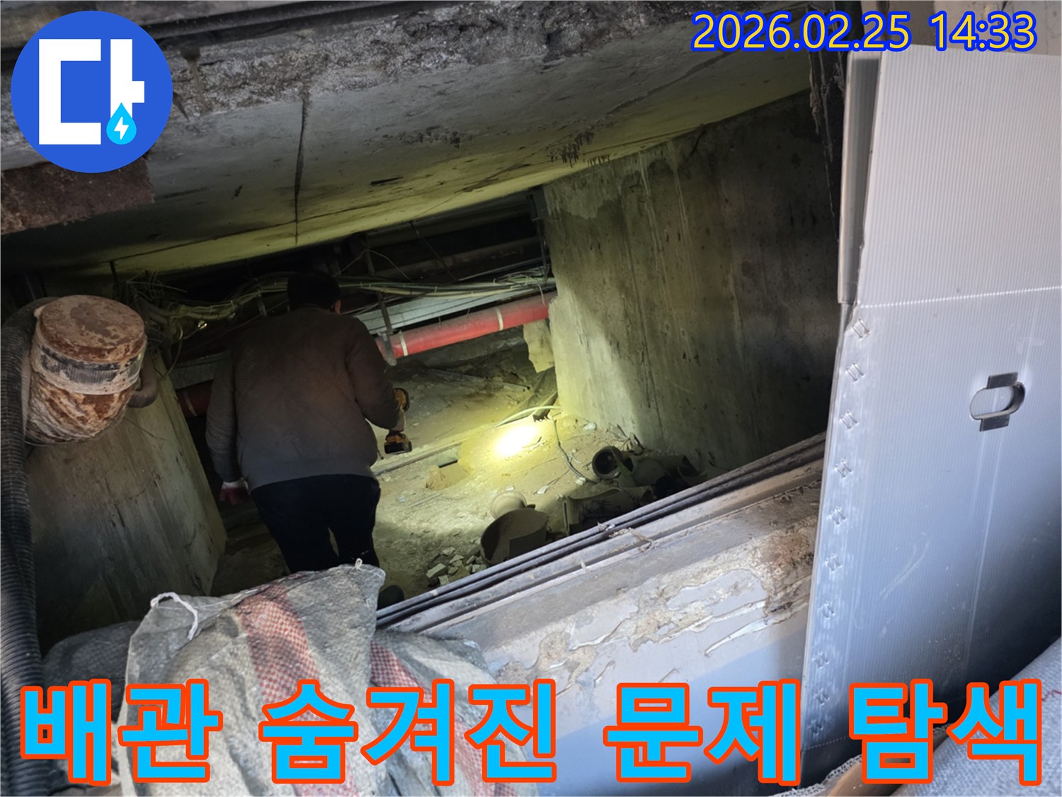 누수 전문 엔지니어가-어둡고 복잡한 배관이 얽힌 공간에서-손전등으로 구석구석을 비추며-배관의 숨겨진 문제점을-정밀하게 탐색하는 전문적인 모습입니다.