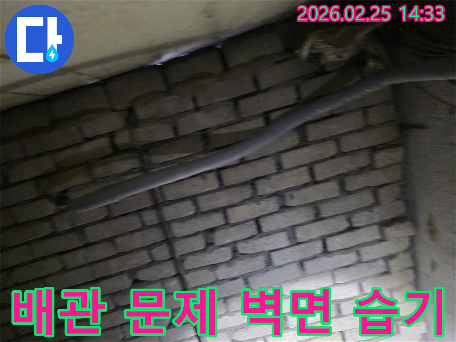 어두운 벽돌 벽면을 배경으로-단열된 배관과 함께-누수로 인한 벽면 습기를-제거하기 위해 검사되는 현장 모습입니다.