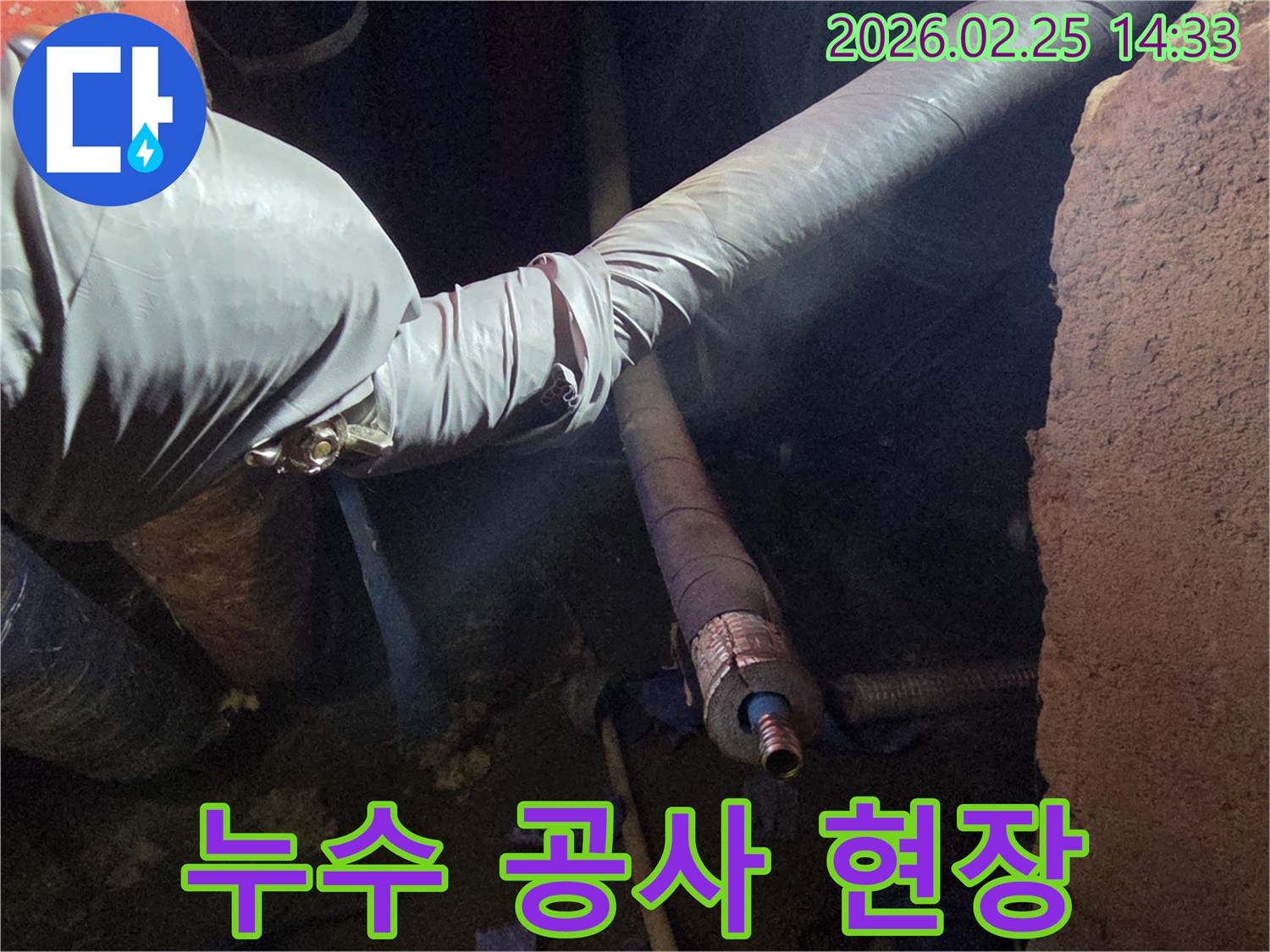어두운 작업 공간에서-장갑을 낀 손이-누수 공사로 발생한-주변의 흙과 잔해를-정리하며-작업을 진행하는-모습입니다