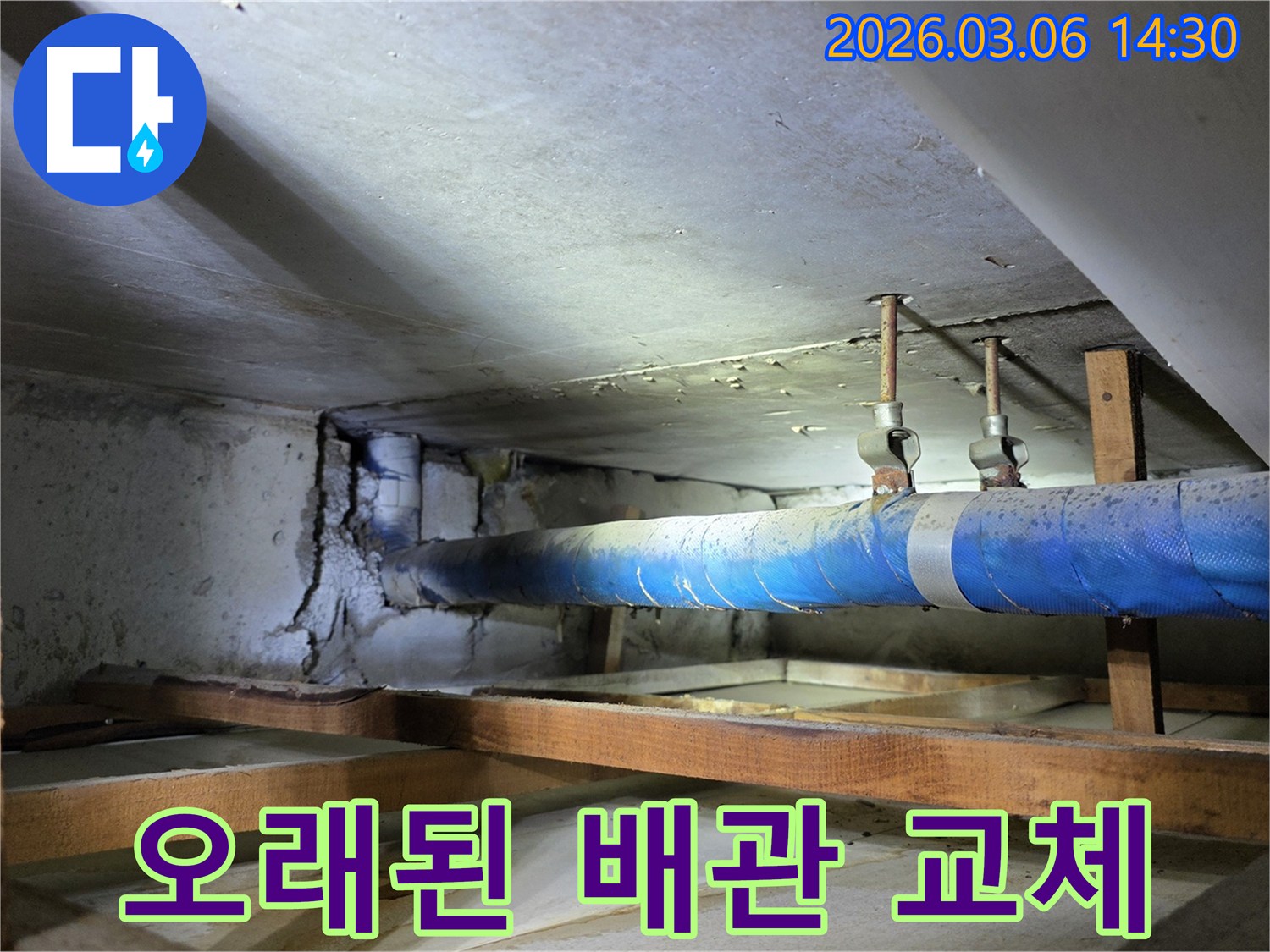 지하 공간의 파란색 배관과-손상된 콘크리트 벽면을-누수 엔지니어가-점검하며 배관 교체 필요성을-진단하는 모습