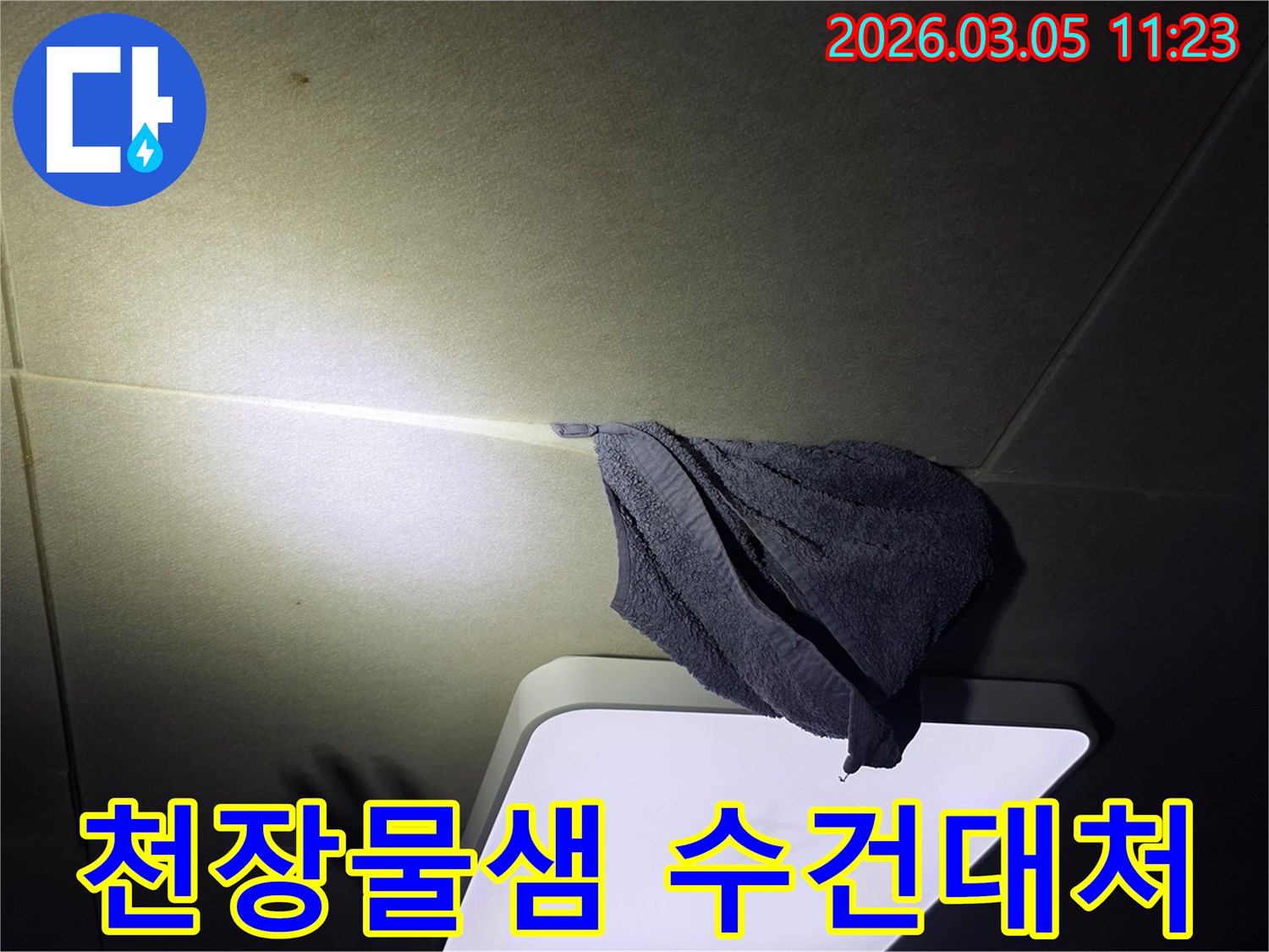 누수로-인해-천장-등기구-주변에-물이-떨어져-수건으로-임시-조치한-모습을-담은-사진