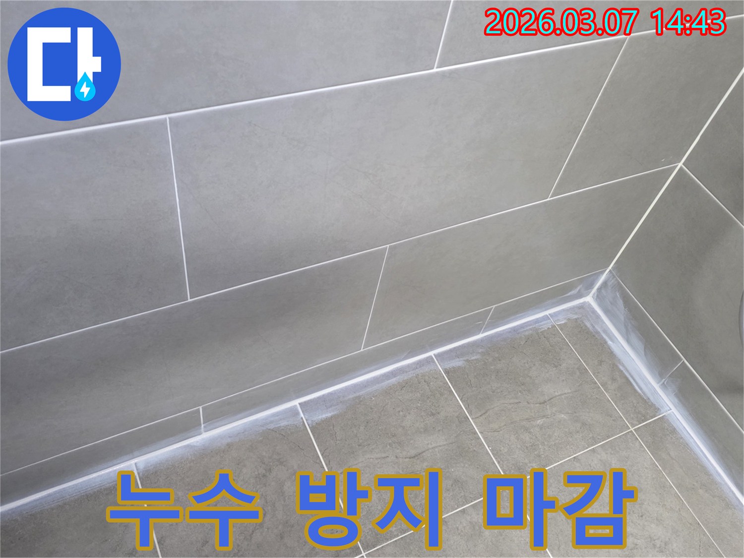 회색 타일로 된-주택 욕실의-벽과 바닥 경계면을-새로운 실리콘으로-튼튼하게 마감하여-누수를 완벽히 방지한 사진