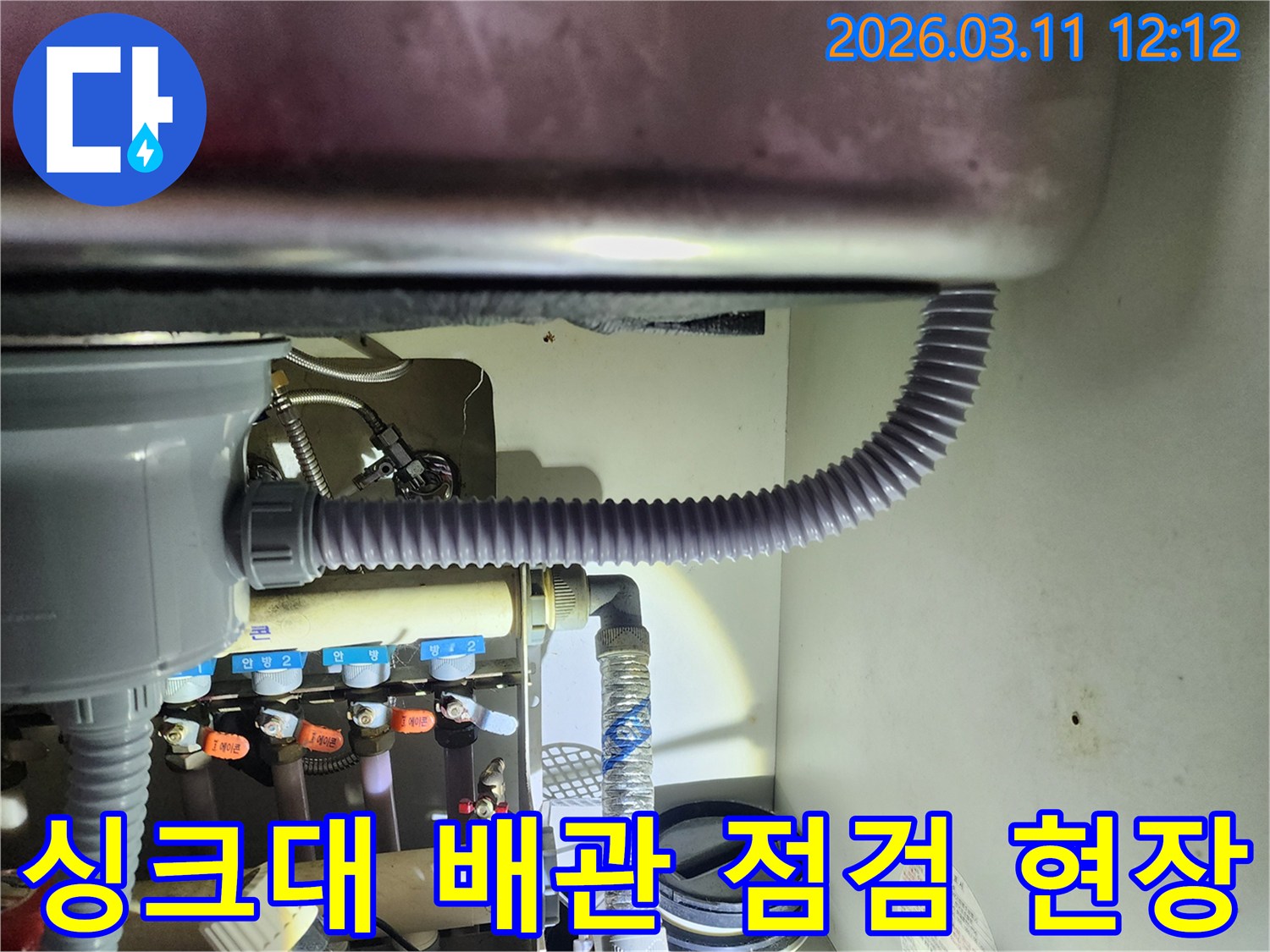 싱크대 하부의-배수관과 주변 배관들을-밝은 조명으로 비춰-누수 여부를-확인하는 모습입니다