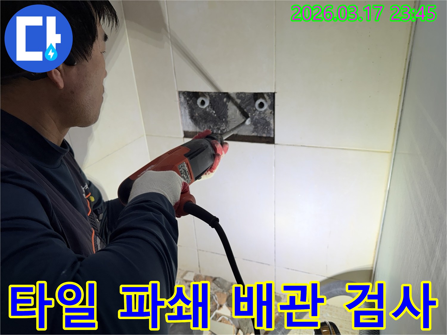 숙련된 기술자가 빌라 누수 지점을 찾아내기 위해-벽면 타일을 깨고 내부 배관을 드러내어-정밀 검사하는 작업을 진행하고 있습니다.