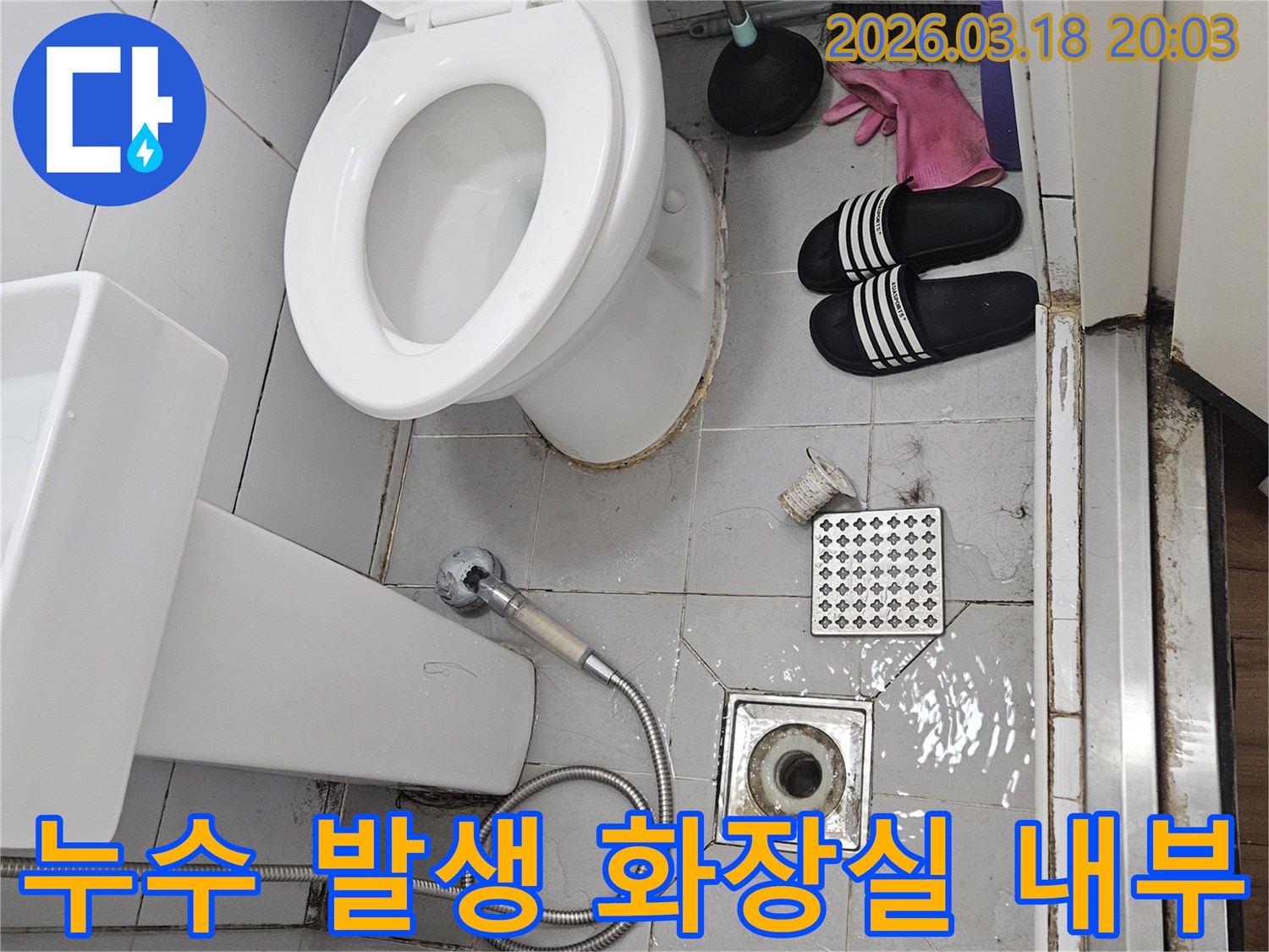 누수로 인해-바닥에 물이 찬-화장실의 모습으로-배수구와-세면대-변기가 함께 찍힌 사진