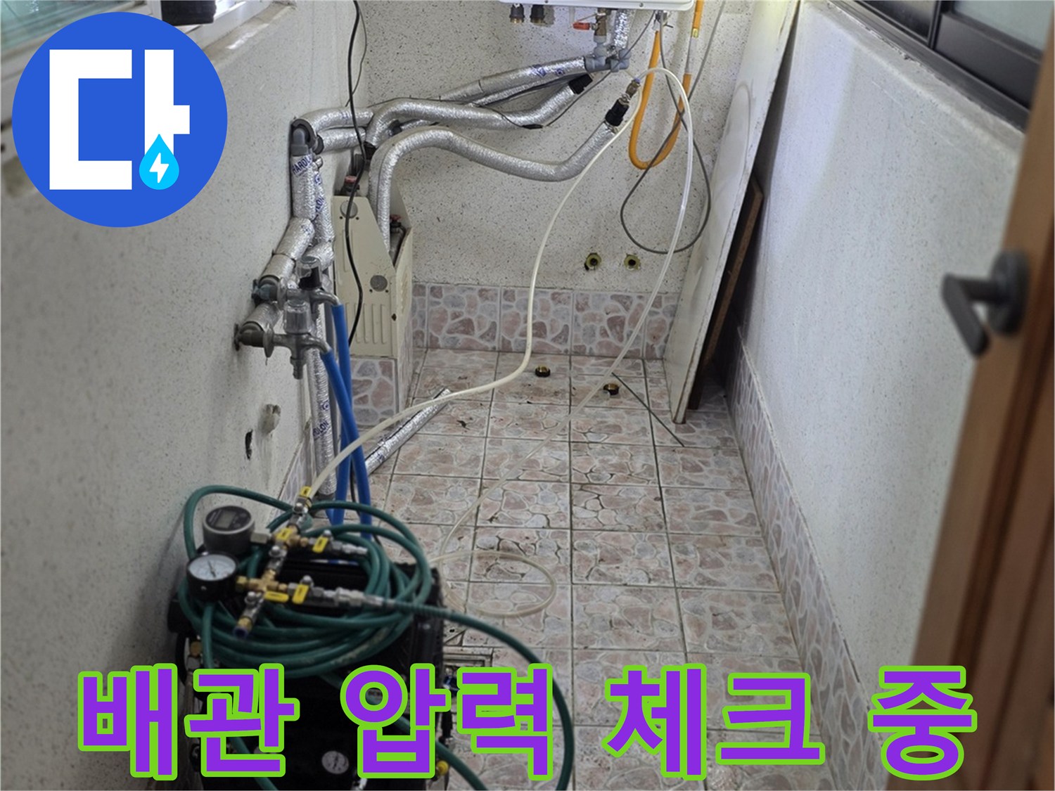 보일러실 배관에 연결된 파란색 호스와 압력 측정 장비의 모습