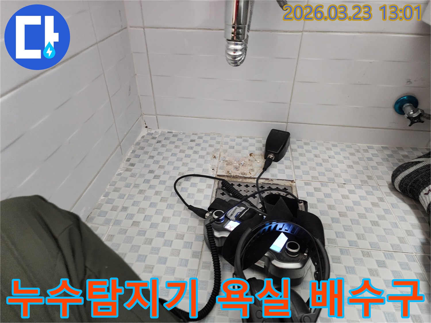 욕실 배수구 근처에 놓인-누수탐지 장비와-헤드폰-그리고-수도관-모습