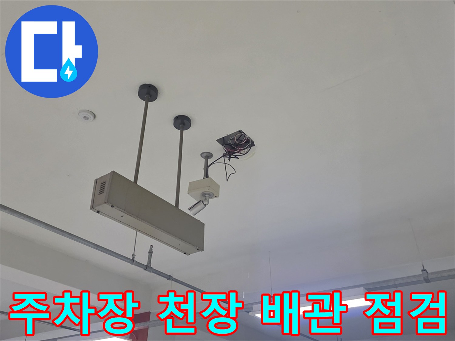 지하 주차장 천장에 설치된 배관과 전기 배선의 상태를 확인하는 모습
