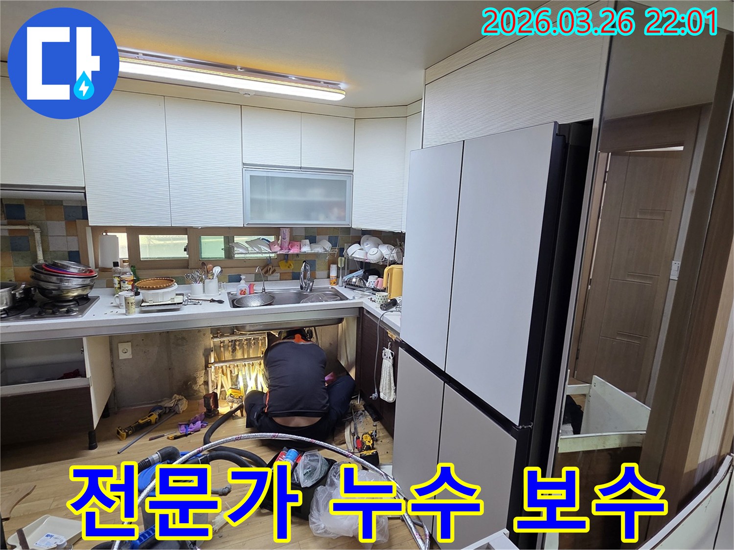 누수 전문 기술자가-싱크대 아래 좁은 공간에서-배관을 점검하고 수리하는 장면입니다