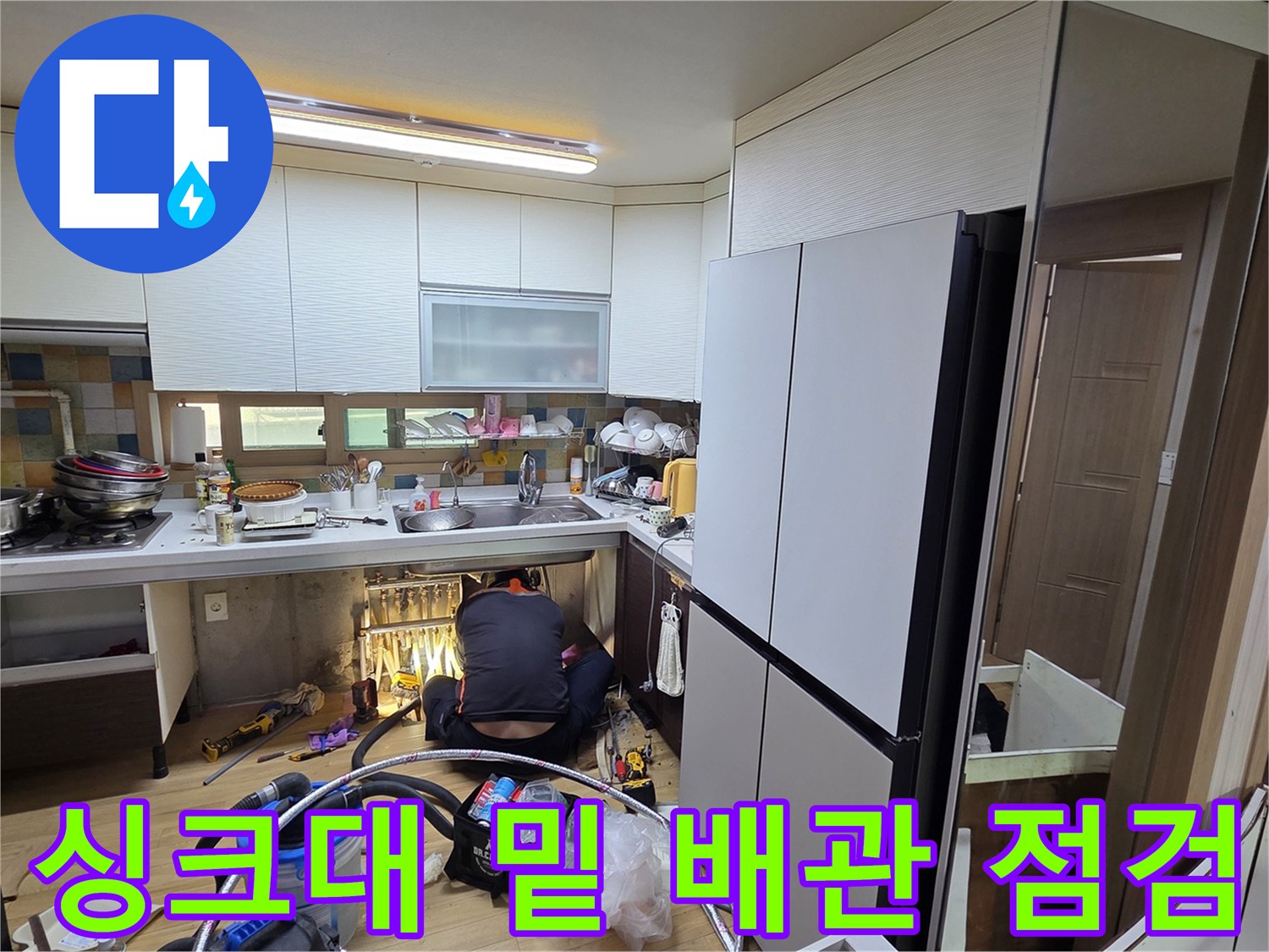 싱크대 하부장 아래 공간에서 진행되는 누수 진단 작업 현장입니다.