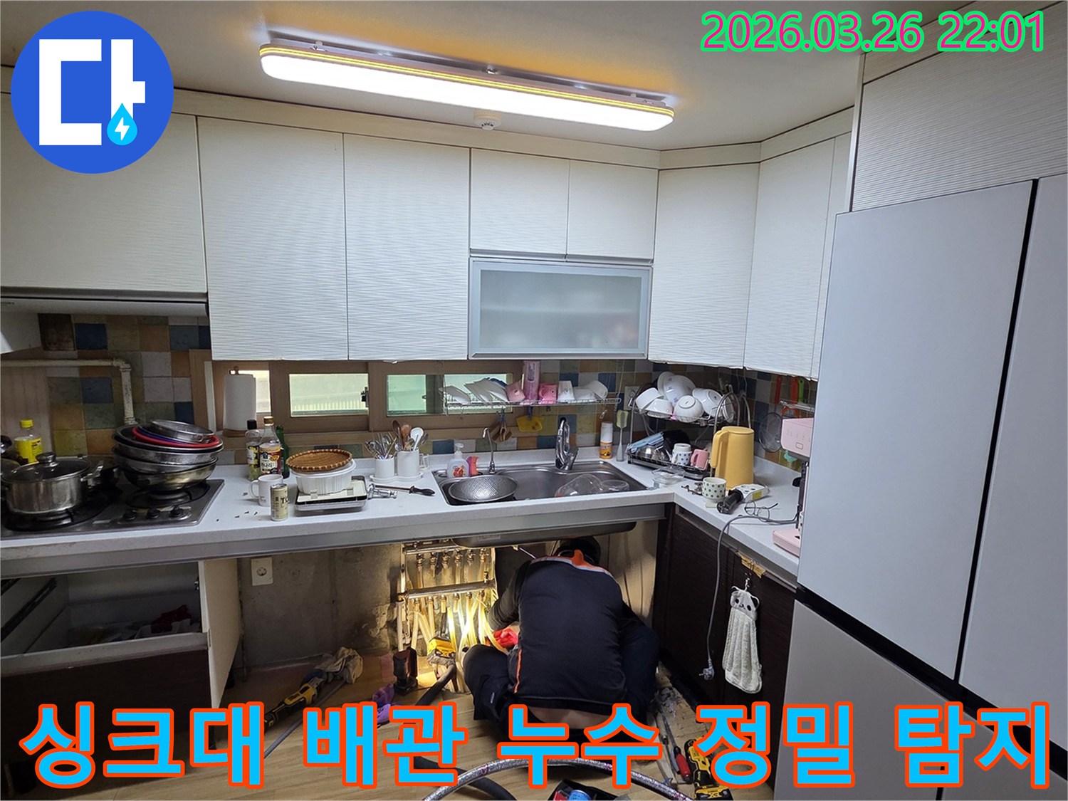 전문가가 주방 싱크대 아래에서 배관 누수 지점을 찾기 위해 집중적으로 탐지하는 장면입니다.
