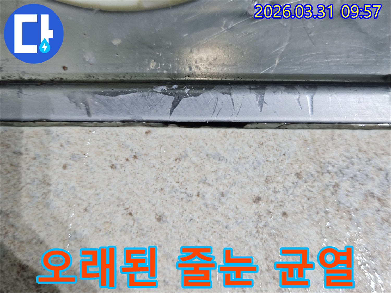 오래되어-갈라지고-손상된-욕실 바닥-줄눈과-배수구 금속 테두리-경계면을-확대한-이미지로-누수 원인을-시각적으로-보여줍니다.