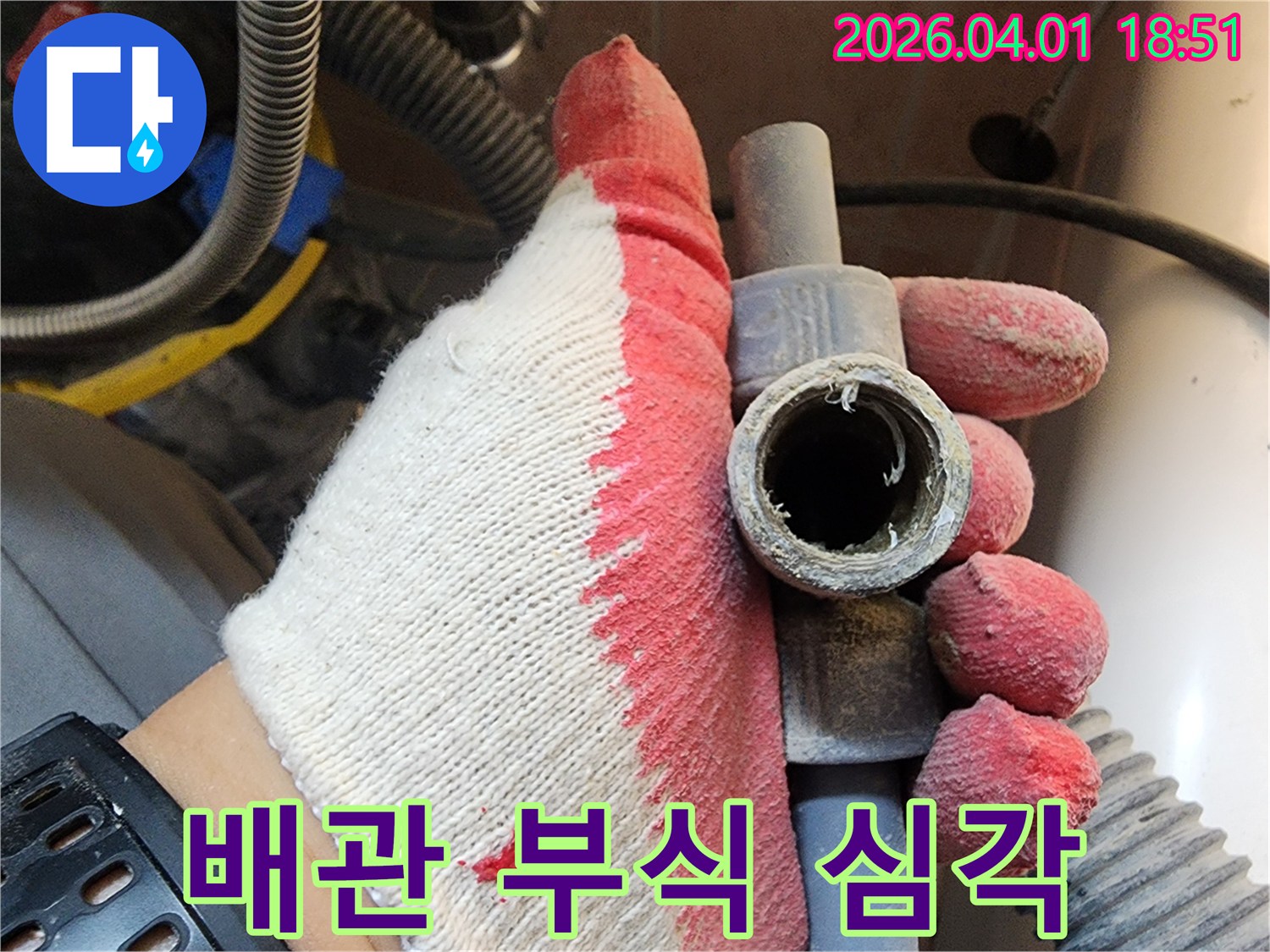 작업용 장갑을 낀 손으로-심하게 부식된 배관의 단면을-보여주며 문제의 심각성을 설명하는 모습