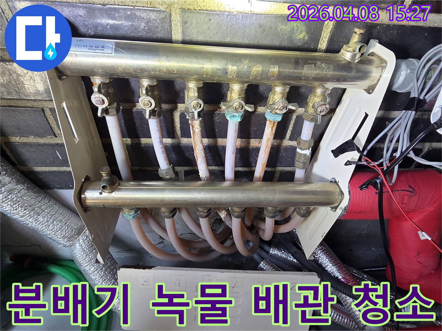오래된-난방-분배기의-밸브와-배관-연결-부위에서-발견된-심한-녹과-부식-현상을-보여주며-녹물-제거와-배관-청소의-필요성을-강조하는-사진
