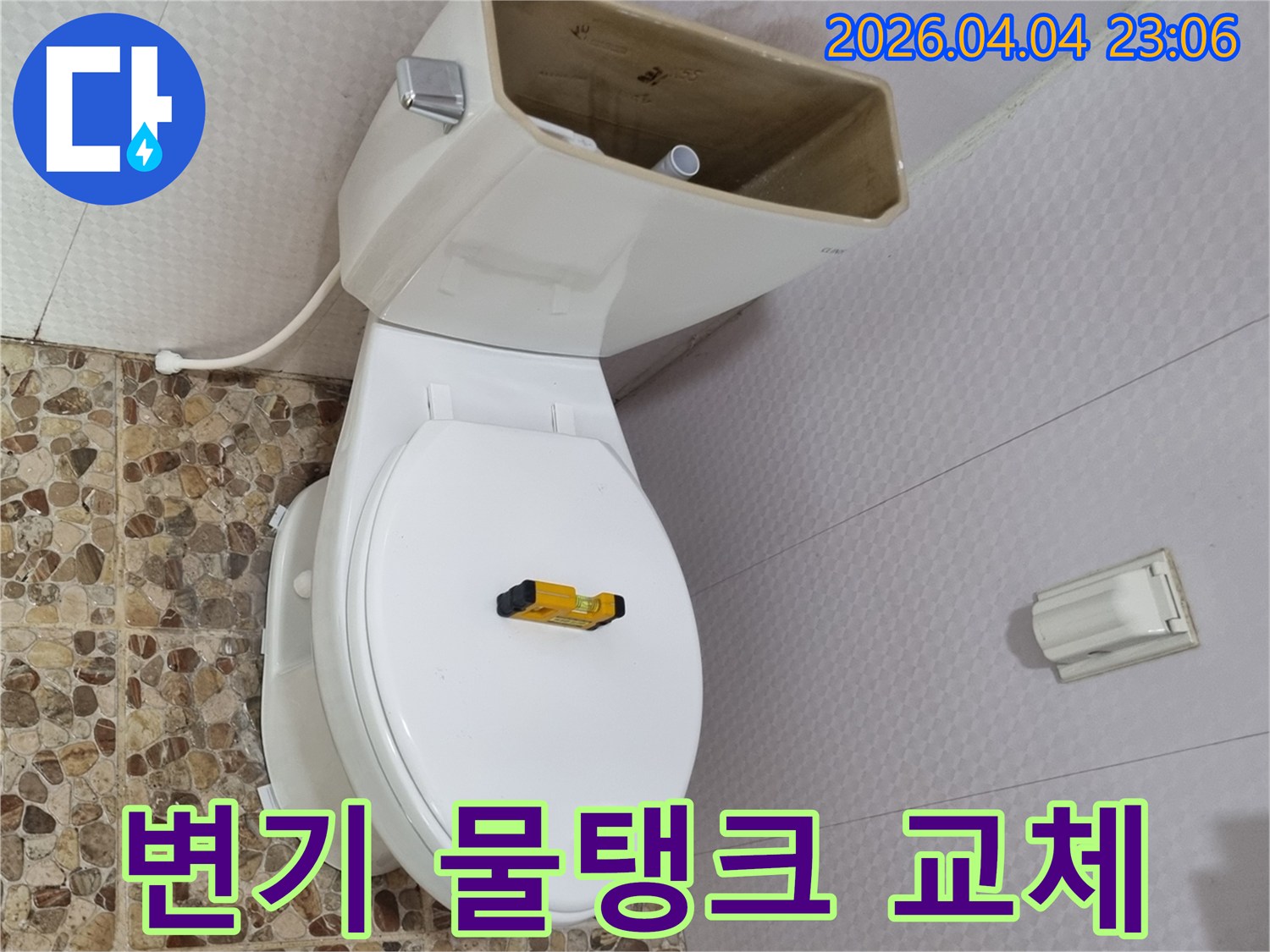 변기 물탱크가 열려 내부 부품이 노출된 상태로-수평계가 변기 시트 위에 놓여-물탱크 교체를 위한 준비가 완료되었습니다
