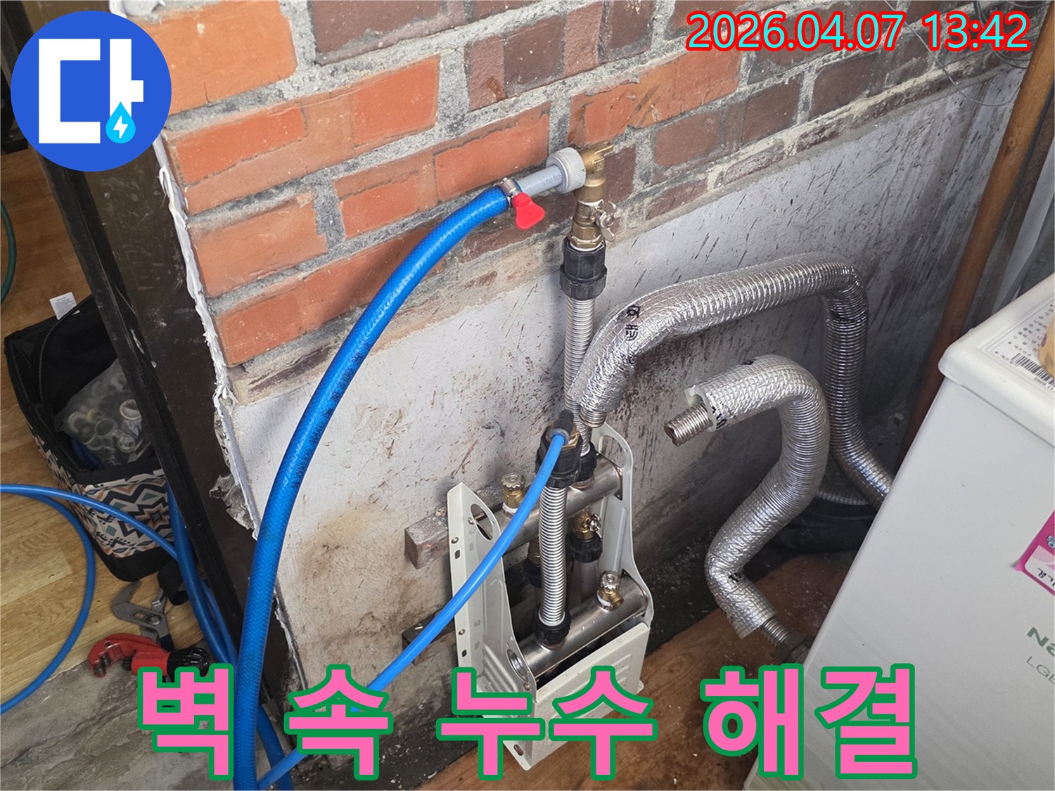 벽돌 벽 옆에-누수 탐지 장비와-배관들이 놓여 있으며-벽 속에 숨어있는-누수를 찾기 위한-정밀 탐지가 진행 중입니다.