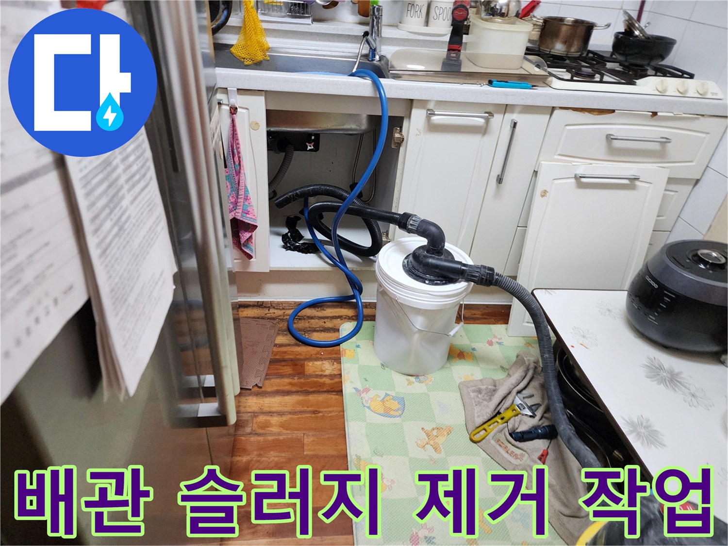 싱크대 하부 배수 호스와 석션기 튜브가 연결되어 오물을 흡입하는 장면입니다.